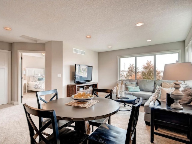 carpeted dining space featuring a textured ceiling