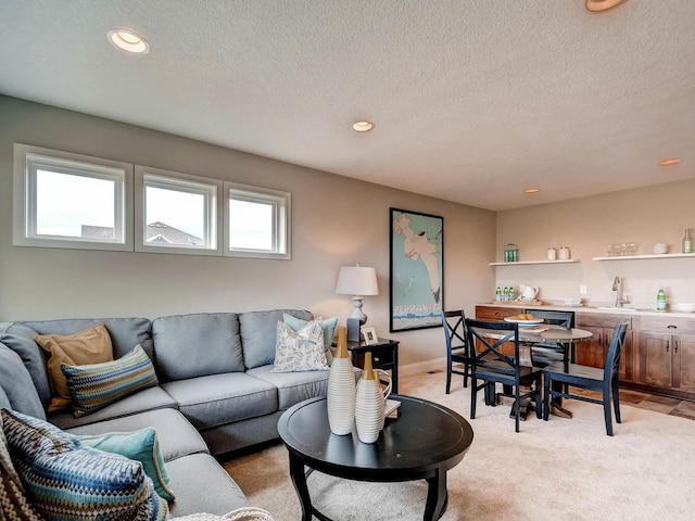 living room with light carpet, a wealth of natural light, sink, and a textured ceiling