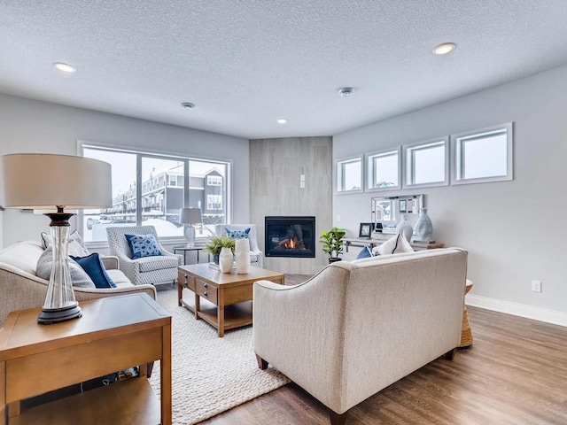 living room featuring hardwood / wood-style flooring, a tiled fireplace, and a textured ceiling