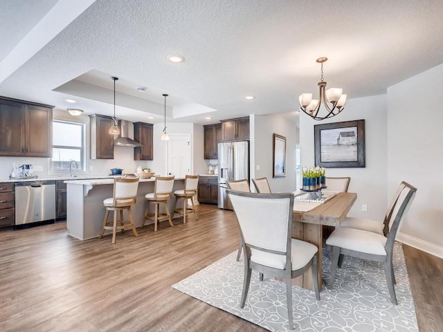 dining space featuring wood-type flooring, an inviting chandelier, a raised ceiling, and a textured ceiling