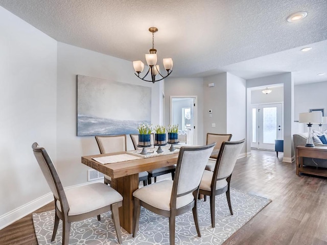 dining area with hardwood / wood-style floors, a chandelier, and a textured ceiling