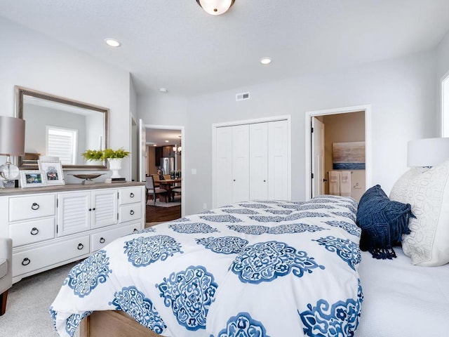 carpeted bedroom with ensuite bathroom and a closet