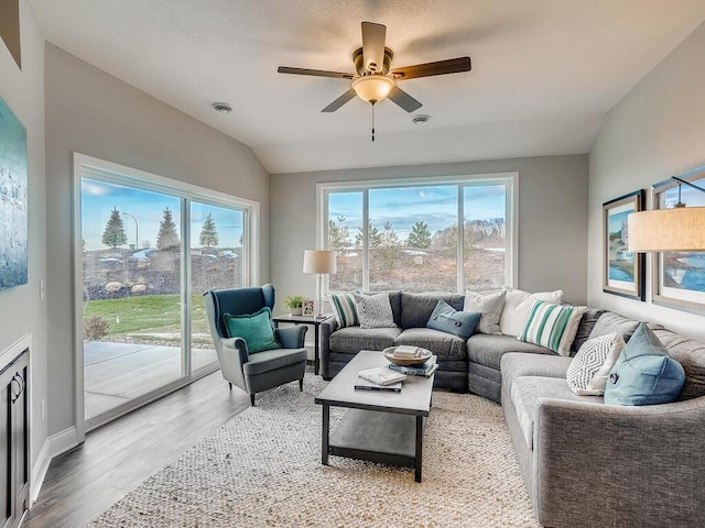 living room featuring wood-type flooring, vaulted ceiling, ceiling fan, and a healthy amount of sunlight