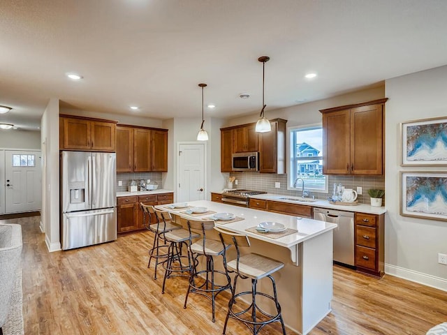 kitchen featuring light wood-type flooring, appliances with stainless steel finishes, a kitchen island, and sink