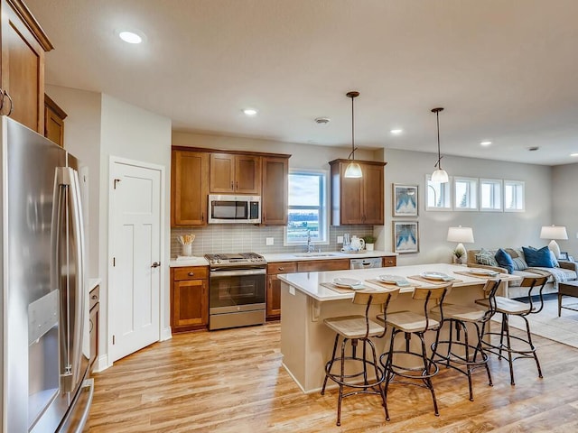 kitchen featuring hanging light fixtures, sink, light hardwood / wood-style flooring, and stainless steel appliances