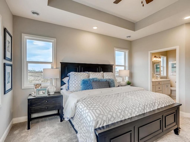 bedroom featuring light carpet, ensuite bathroom, and ceiling fan