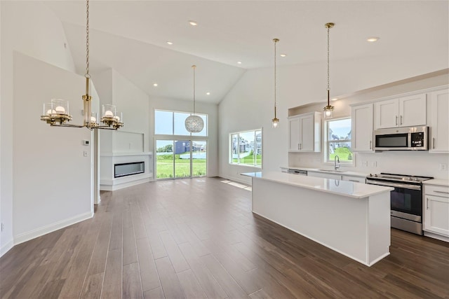 kitchen with appliances with stainless steel finishes, a center island, pendant lighting, and white cabinets