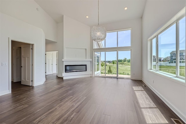 unfurnished living room with plenty of natural light, dark wood-type flooring, and high vaulted ceiling