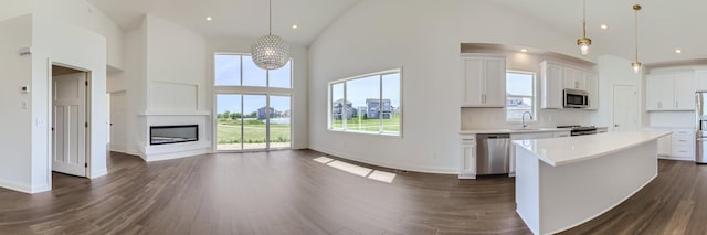 kitchen with pendant lighting, stainless steel appliances, high vaulted ceiling, and a center island