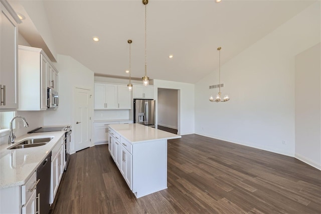 kitchen with a center island, sink, white cabinets, hanging light fixtures, and appliances with stainless steel finishes