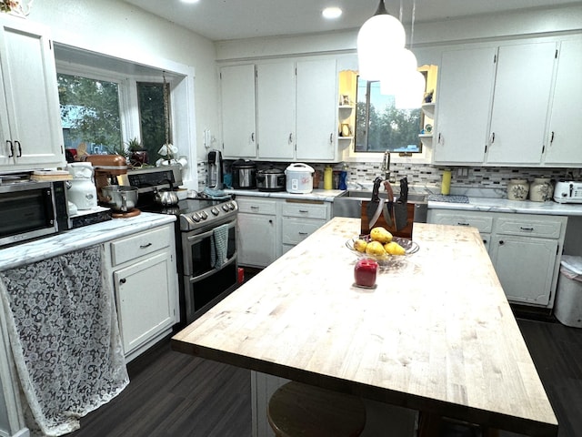 kitchen featuring white cabinets, hanging light fixtures, a kitchen island, appliances with stainless steel finishes, and dark hardwood / wood-style floors