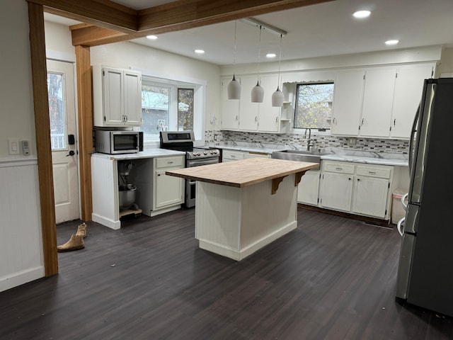 kitchen with a center island, appliances with stainless steel finishes, white cabinets, and dark hardwood / wood-style flooring