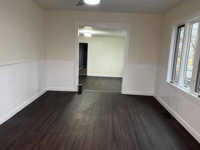 empty room featuring dark wood-type flooring and ceiling fan