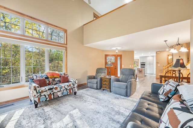 living room with a high ceiling, wood-type flooring, and an inviting chandelier