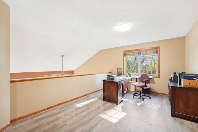 office area with lofted ceiling, light hardwood / wood-style flooring, and a textured ceiling