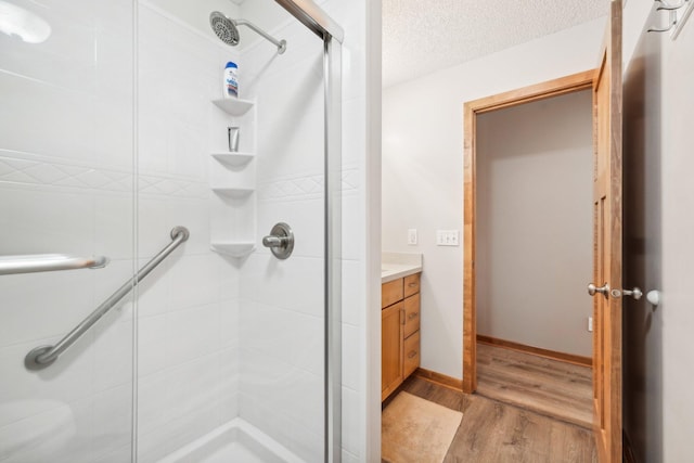 bathroom featuring vanity, a textured ceiling, wood-type flooring, and walk in shower