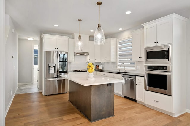 kitchen with white cabinets, light hardwood / wood-style floors, decorative light fixtures, and appliances with stainless steel finishes