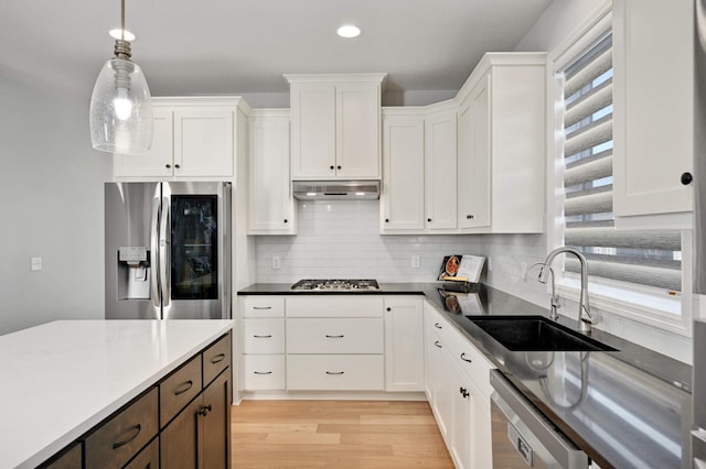 kitchen with sink, white cabinets, decorative light fixtures, and appliances with stainless steel finishes