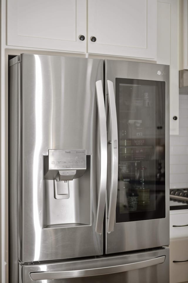 details with stainless steel fridge with ice dispenser and white cabinets