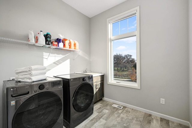 clothes washing area with washer and dryer, light hardwood / wood-style floors, cabinets, and sink