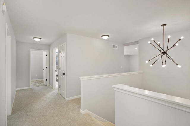 corridor with a notable chandelier and light colored carpet