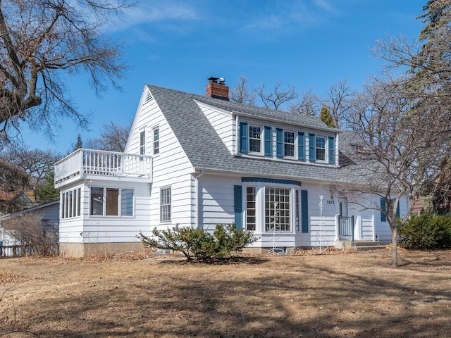 view of front of house with a balcony, a chimney, and roof with shingles