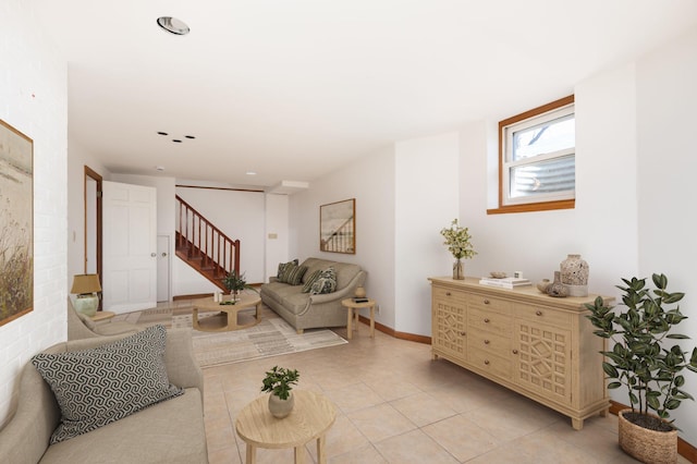 living area featuring light tile patterned floors, stairway, and baseboards