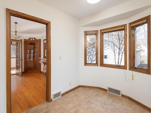 spare room featuring visible vents, light wood-type flooring, and baseboards