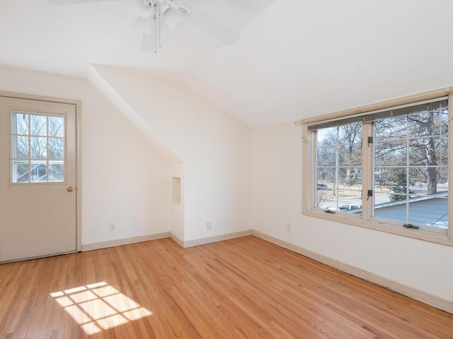 additional living space featuring a wealth of natural light, baseboards, lofted ceiling, and light wood-style floors