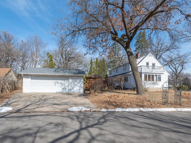 view of front of property featuring a detached garage, a balcony, an outdoor structure, and a chimney