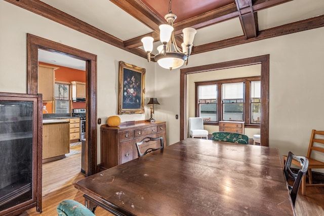 dining space featuring coffered ceiling, beamed ceiling, a chandelier, and light hardwood / wood-style floors