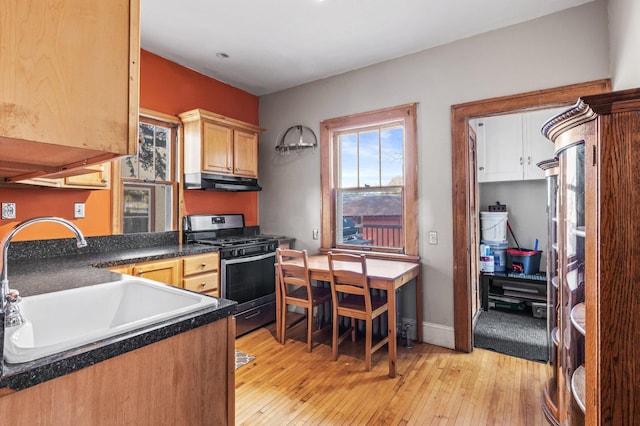 kitchen featuring gas stove, light brown cabinetry, sink, and light wood-type flooring