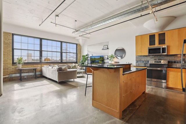 kitchen featuring concrete floors, stainless steel appliances, a breakfast bar, and a center island