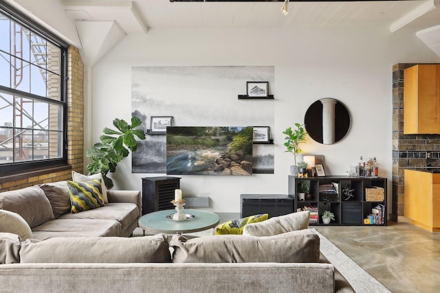 living room featuring beamed ceiling and concrete floors