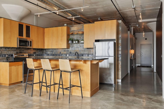 kitchen featuring dark stone countertops, a kitchen island, stainless steel appliances, tasteful backsplash, and a kitchen bar