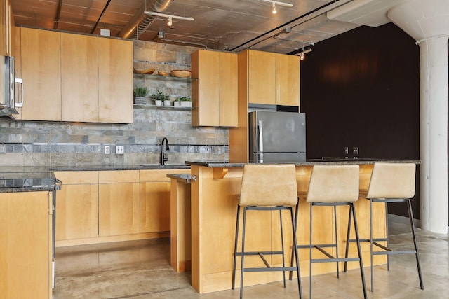 kitchen featuring sink, a breakfast bar area, stainless steel refrigerator, a kitchen island, and decorative backsplash