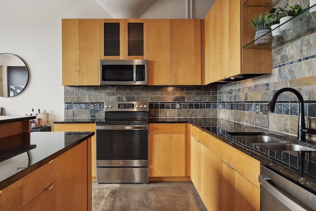 kitchen with appliances with stainless steel finishes, sink, decorative backsplash, and dark stone counters