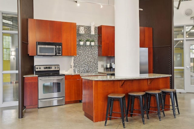 kitchen with a kitchen island, tasteful backsplash, sink, light stone counters, and stainless steel appliances