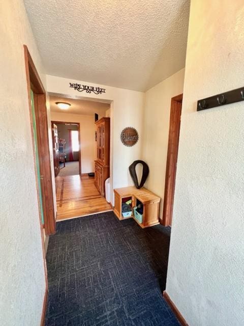 hallway with a textured ceiling and dark wood-type flooring