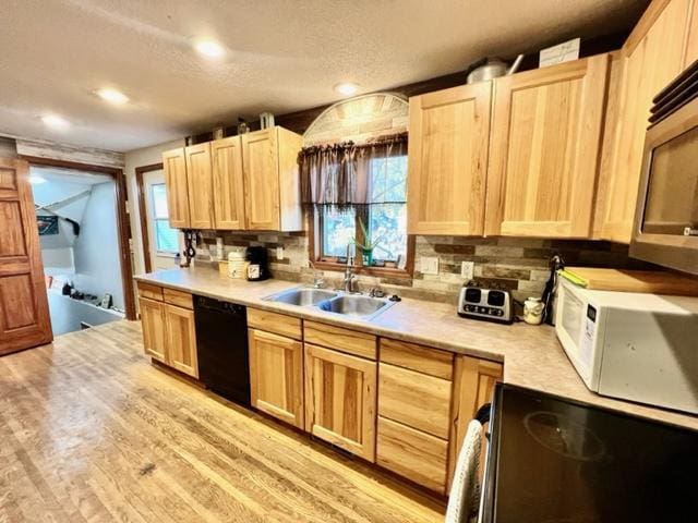 kitchen featuring light brown cabinets, black dishwasher, stove, light hardwood / wood-style floors, and sink