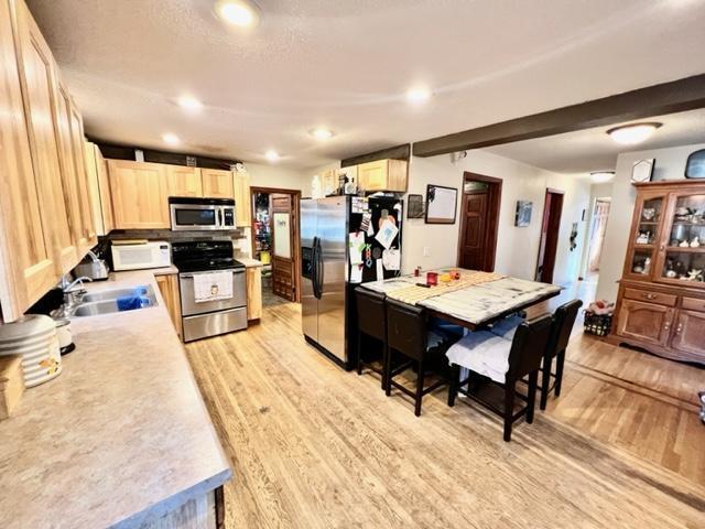 kitchen featuring appliances with stainless steel finishes, light brown cabinets, sink, and light hardwood / wood-style floors