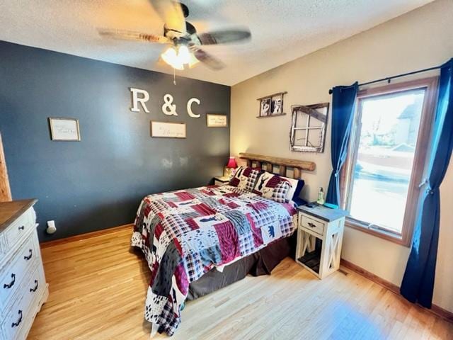 bedroom featuring light hardwood / wood-style flooring, a textured ceiling, and ceiling fan