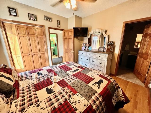 bedroom with a closet, ceiling fan, a textured ceiling, and light wood-type flooring