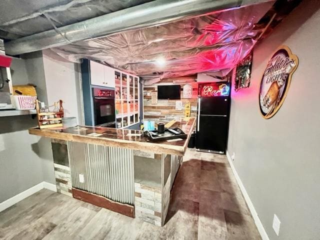 bar with white cabinetry, black appliances, and hardwood / wood-style floors