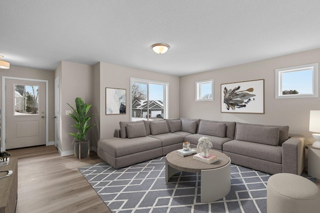living room with light wood-style flooring, baseboards, and a textured ceiling