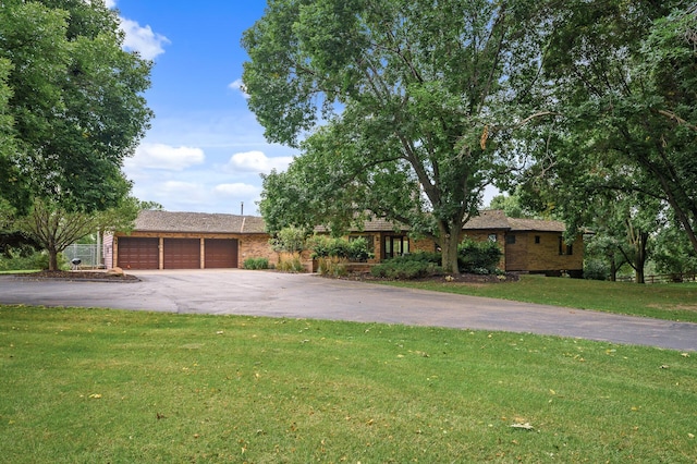 single story home featuring brick siding, a garage, driveway, and a front yard