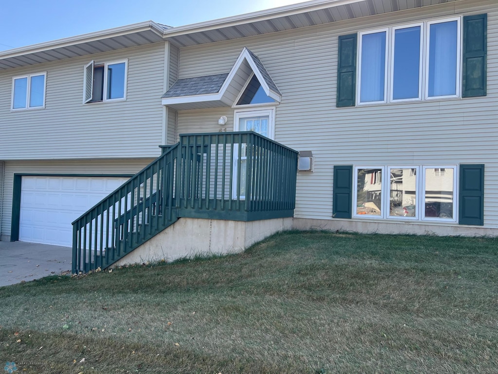 back of house with a garage and a lawn