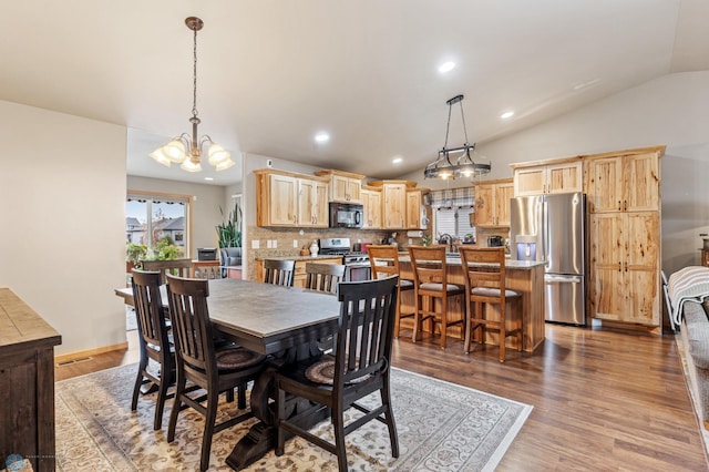 dining area featuring a notable chandelier, lofted ceiling, and hardwood / wood-style floors