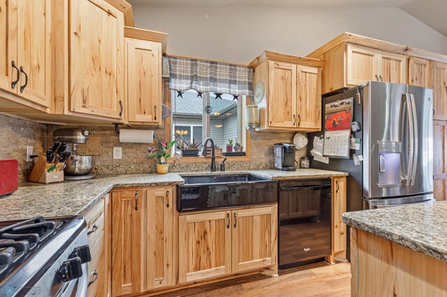 kitchen with lofted ceiling, stainless steel appliances, sink, light wood-type flooring, and light stone counters