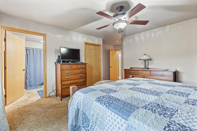 bedroom with light carpet, ensuite bath, and ceiling fan